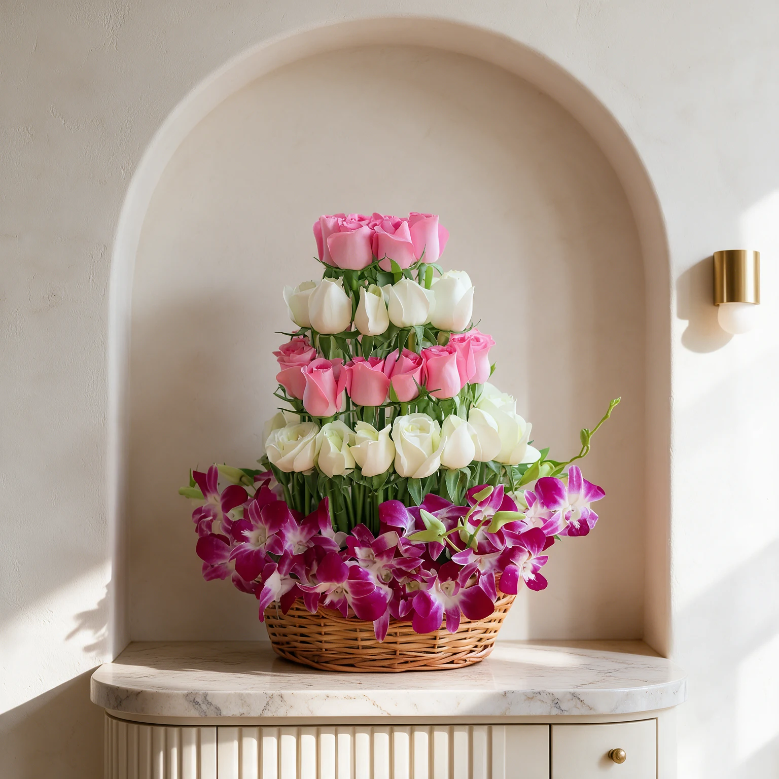 Tiered arrangement of pink and white roses above magenta orchids in a woven basket with lush green foliage.