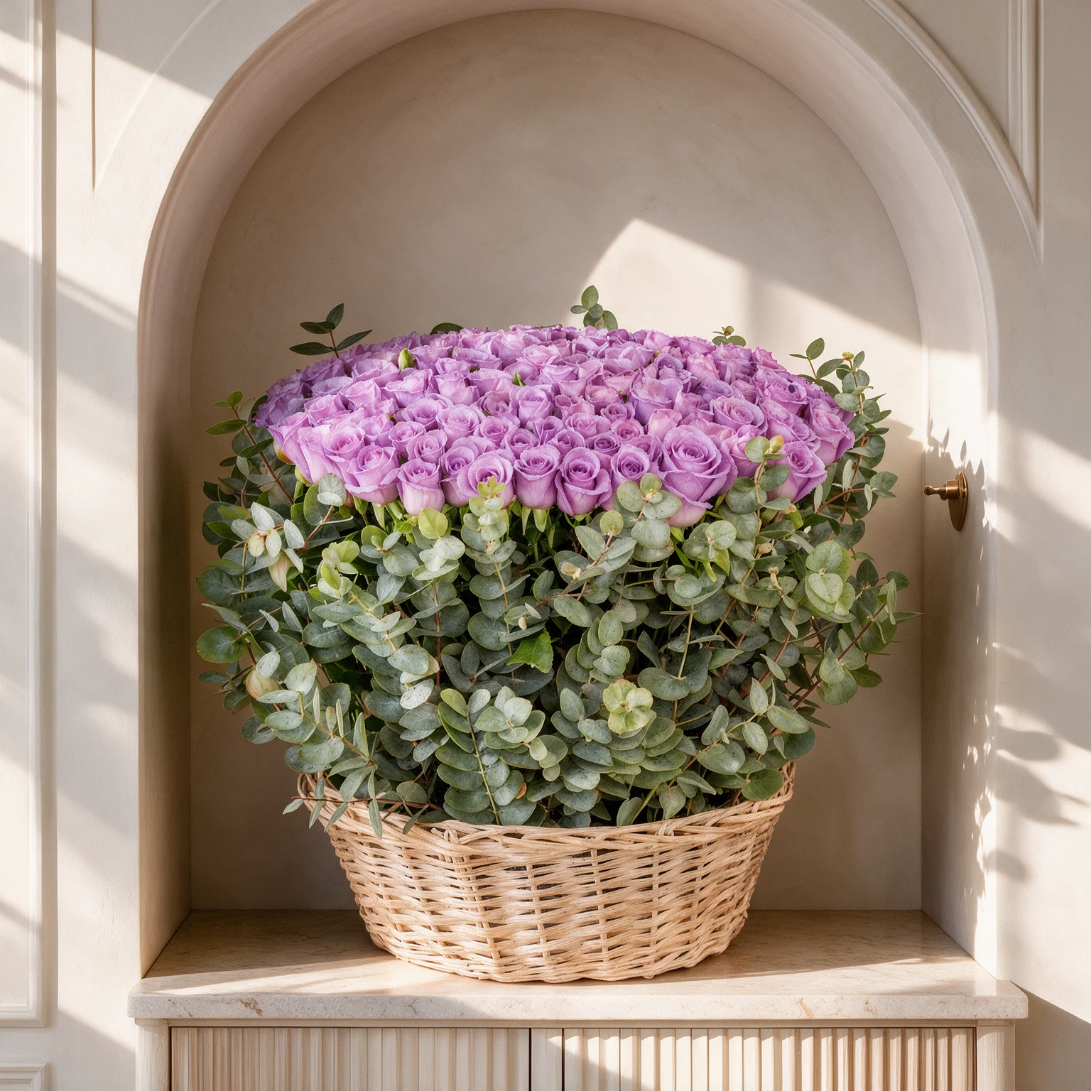 Luxury basket arrangement of 100 purple roses surrounded by eucalyptus foliage for an elegant and sophisticated floral display.