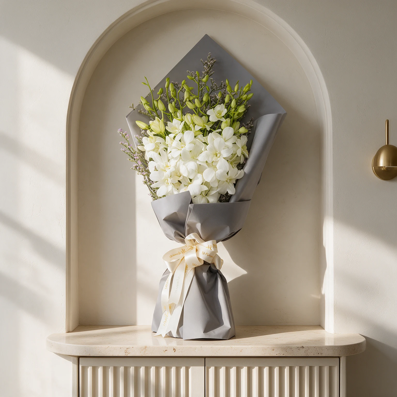 White orchids with green buds and delicate filler stems, wrapped in grey paper and finished with a cream ribbon.